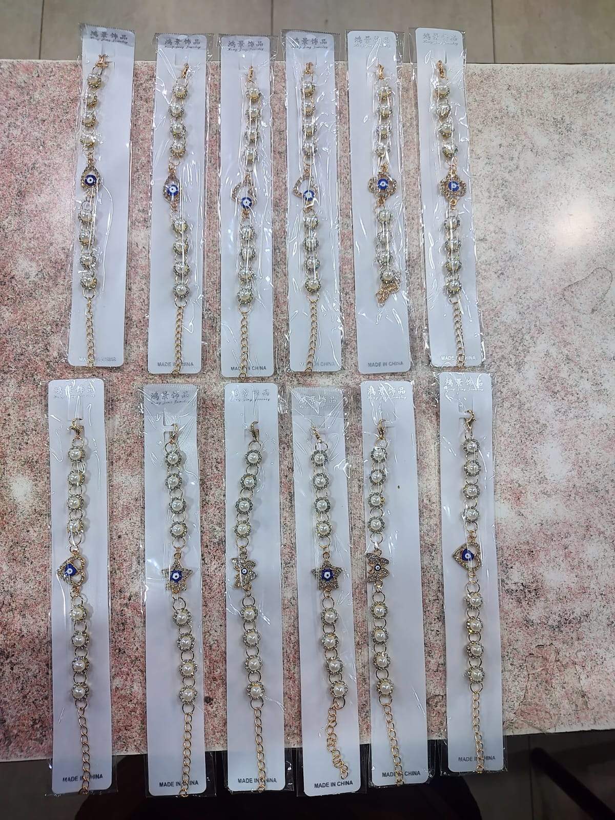 ✨ Pulsera Dorada con Perla, Ojo Turco y Dijes Variados – Por Docena ✨